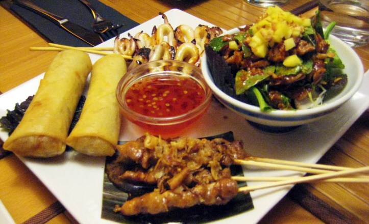 Surtido de entrantes: rollitos vegetarianos, brochetas de calamar, ensalada con pato y brochetas de pollo con salsa de cacahuetes